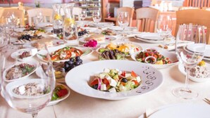 A restaurant setting with multiple tables set for dining, various dishes, and wine glasses.