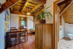 A wooden dining area with a table and chairs, a wooden cabinet, and a hanging plant. - Hotel Leyla (Frymburk)