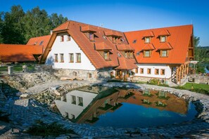 Un edificio tradizionale con tetto spiovente e diverse finestre, riflesse in uno stagno.