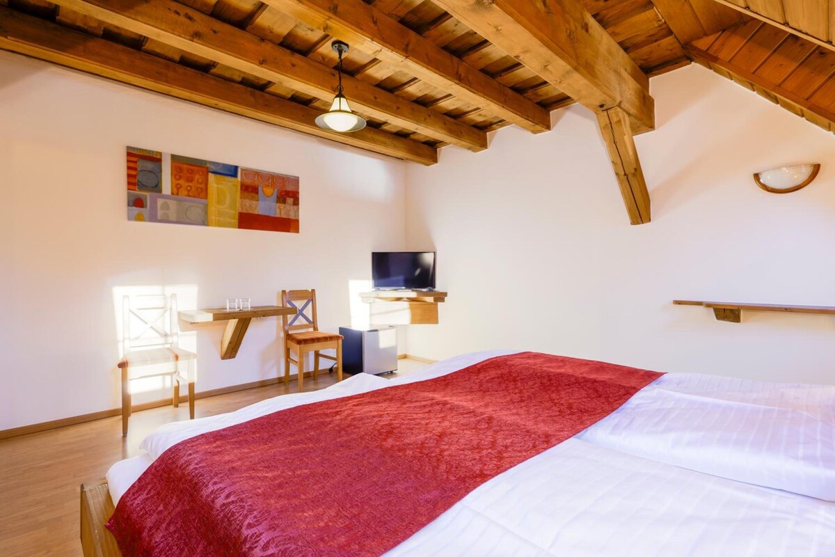 Ein Schlafzimmer mit einem Bett, einem Schreibtisch, einem Sessel, einem Fernseher und Bildern an der Wand.