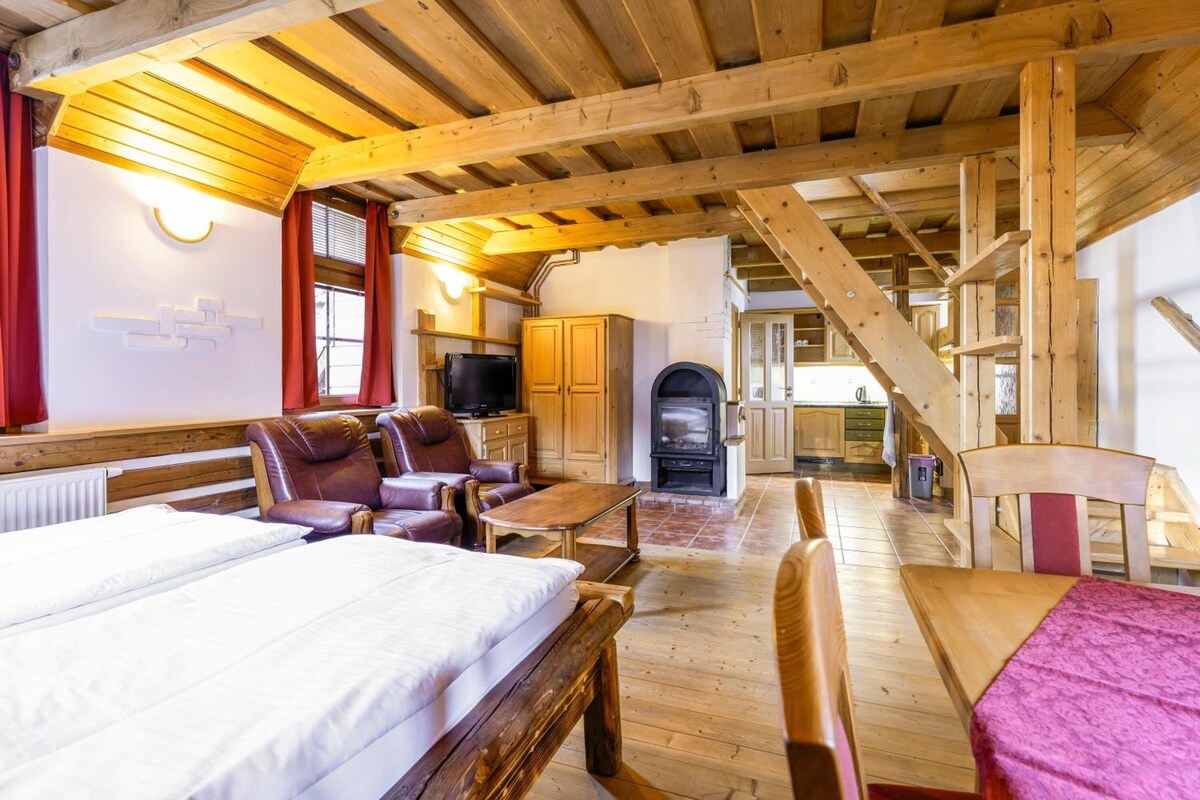 A cozy room with a bed, a sofa, a table, and a fireplace.