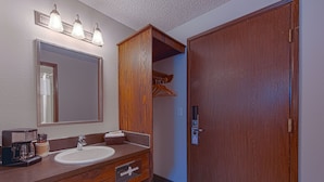 A bathroom with a wooden vanity, a sink, a mirror, and a door. - Silver Inn (Kellogg)