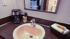 A bathroom sink with a coffee maker, a cup, and a towel dispenser. - Silver Inn (Kellogg)