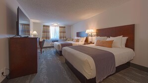 A hotel room with two beds, a desk, and a TV. - Silver Inn (Kellogg)