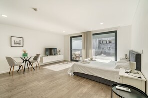 Una habitación de hotel moderna con cama, escritorio, televisión y un gran ventanal con vista a la ciudad.