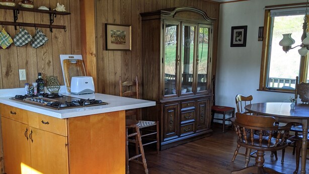 Una cocina con armarios de madera, una isla central y un comedor con mesa y sillas.