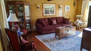 Una sala de estar acogedora con un sofá rojo, una mesa de centro de madera y un tapete estampado.