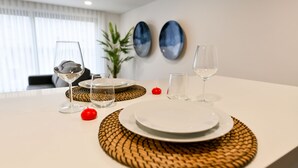 Una mesa de comedor dispuesta con platos, vasos y un adorno rojo.
