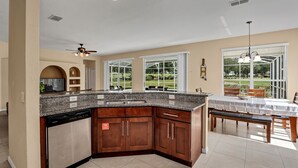 A kitchen with a dishwasher, a ceiling fan, and a dining area with a table and chairs. - Family Villa With Pool and Golf, 20 Mins To Disney (Davenport)