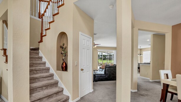 A home interior with a carpeted staircase, a dining area, and a living room with a sofa and a coffee table. - Family Villa With Pool and Golf, 20 Mins To Disney (Davenport)