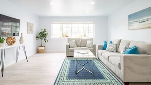 A modern living room with a sofa, coffee table, and a large window. - FAST WiFi, NEW 1 Block to Beach Sparkling Clean A/C BBQ Parking (San Diego)