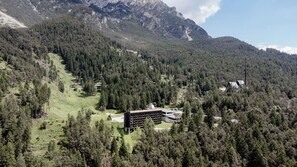 A mountain lodge with multiple buildings surrounded by dense forest and rocky mountains. - Hotel Boite (Borca di Cadore)