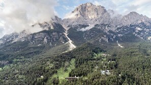 Paesaggio montuoso con una vetta imponente, una valle con edifici sparsi e una strada che si inerpica sulla montagna.