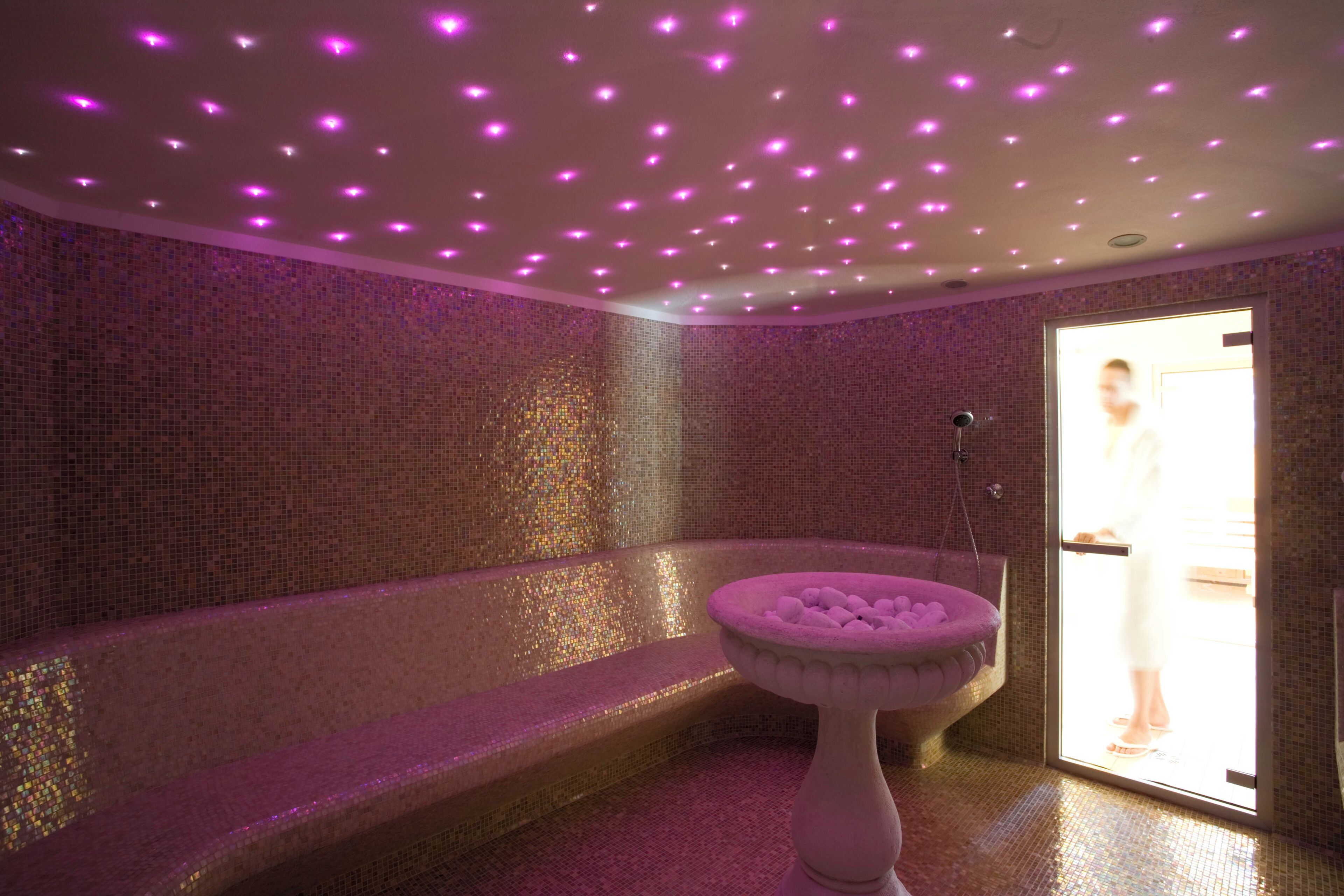 Una spa con vasca da bagno, lavabo decorativo e soffitto illuminato di viola.