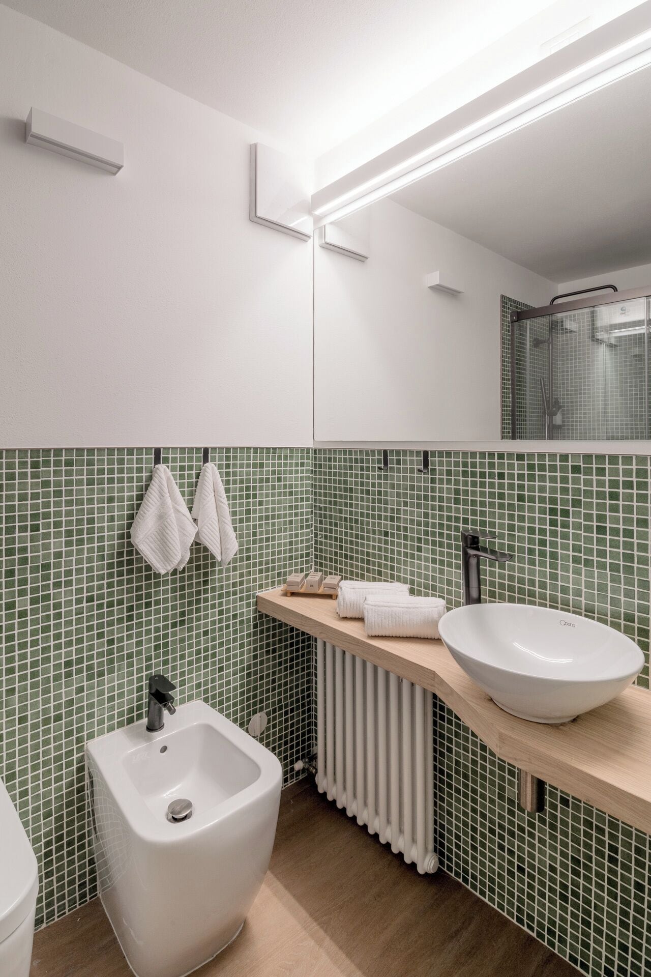 A modern bathroom with a white sink, a bidet, and a mirror.