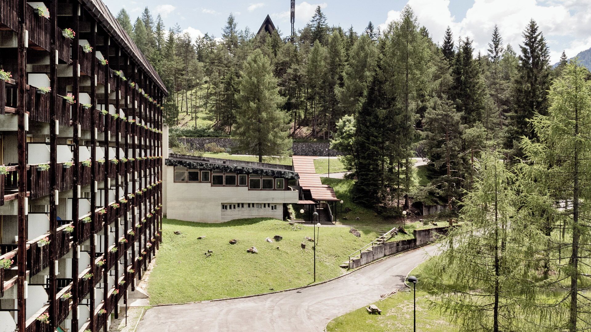 A modern building with a unique wooden facade and a small annex with a sloped roof.