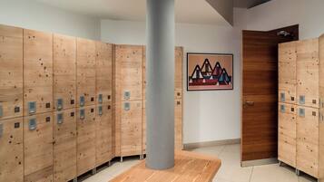 A row of wooden lockers with numbered compartments, a gray pillar, and a door with a wooden panel.
