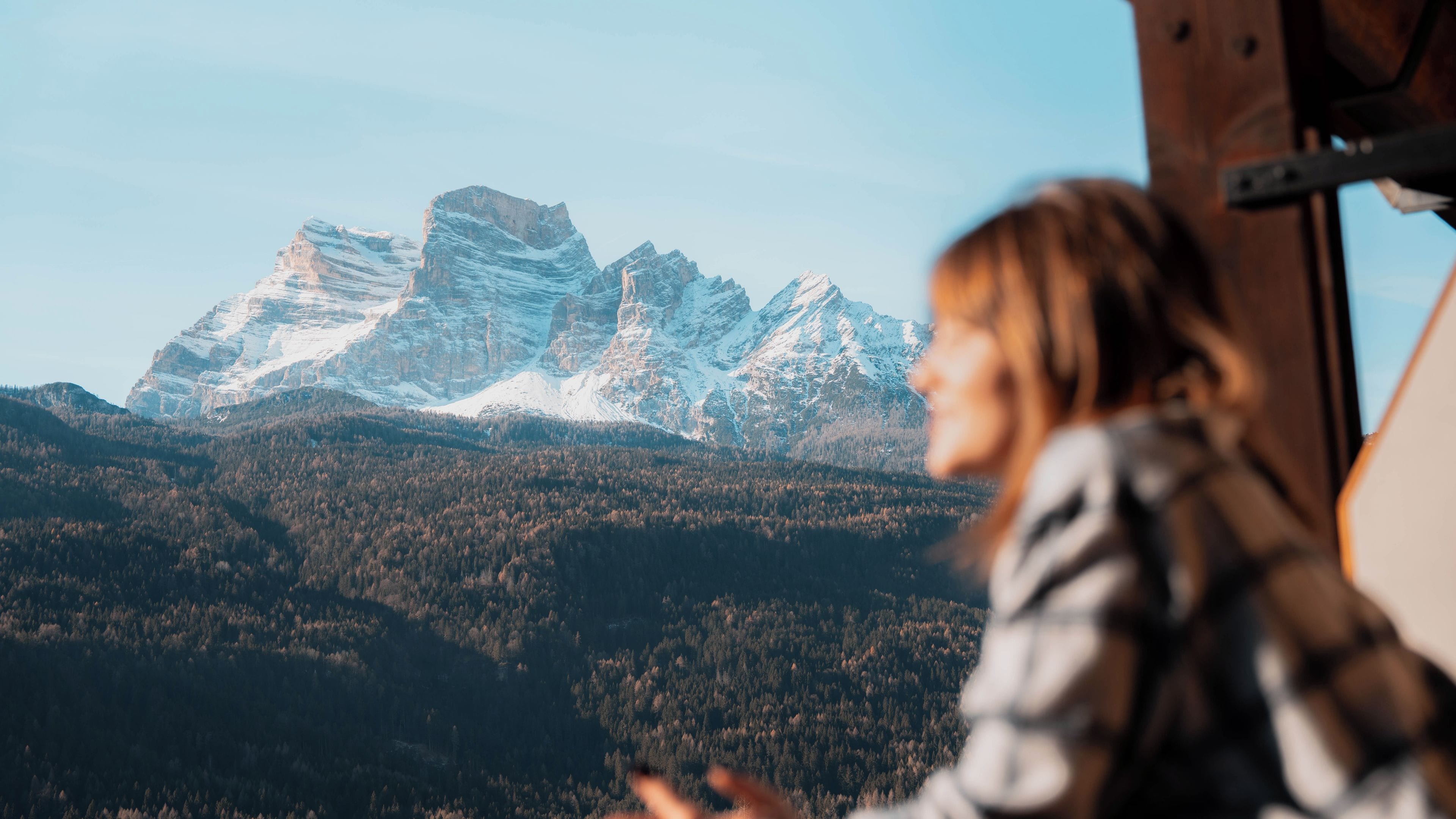 A person looking out at a mountainous landscape with snow-capped peaks.