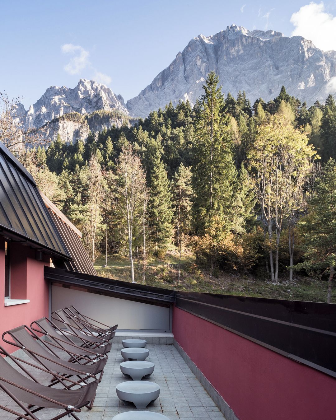 Une terrasse sur le toit, dotée de chaises longues et offrant une vue sur un paysage montagneux.