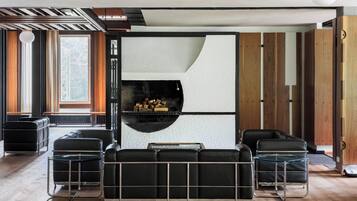 A modern living room with a built-in fireplace, black leather sofas, and a glass coffee table.