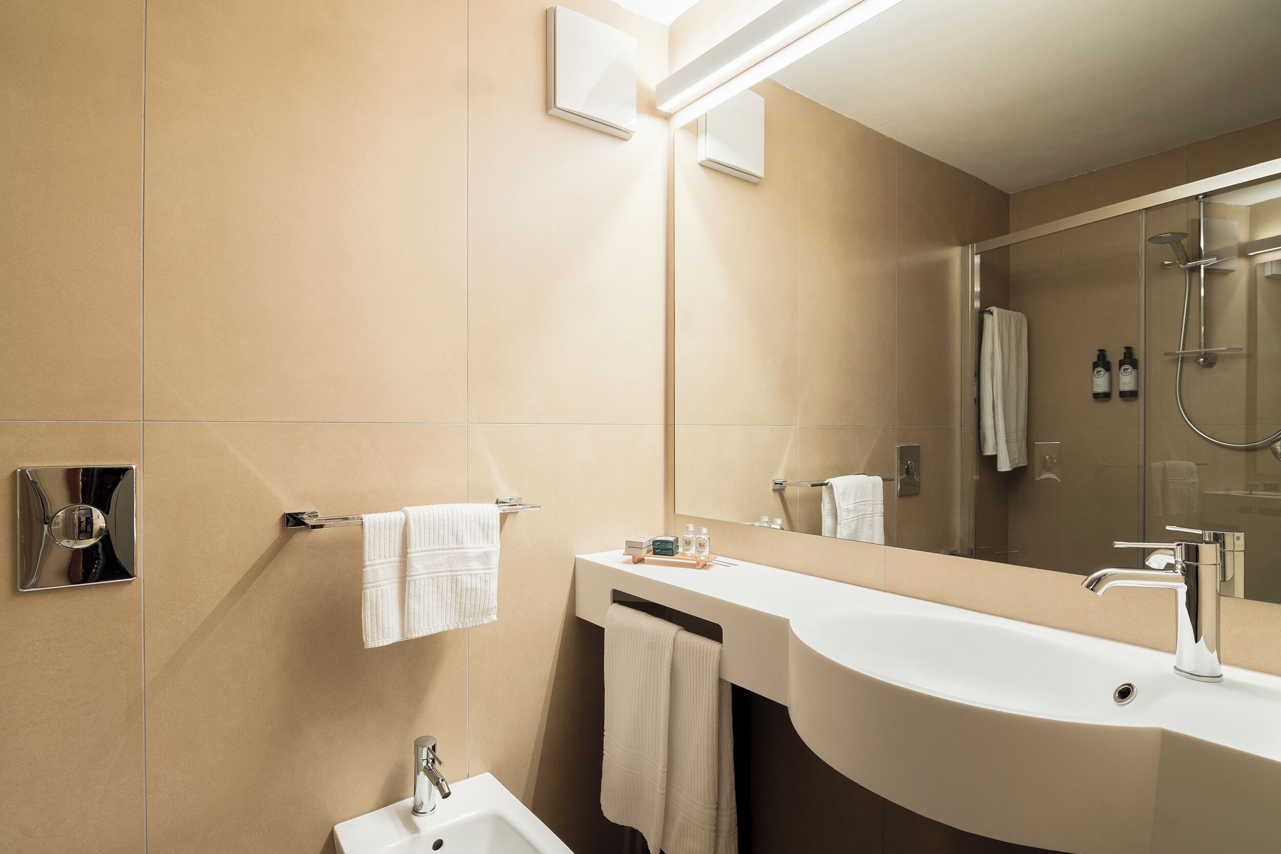 Un bagno moderno con un grande specchio, un lavandino e una doccia.