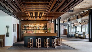 A bar area with wooden slats on the ceiling, a bar counter, and stools. - Hotel Boite (Borca di Cadore)