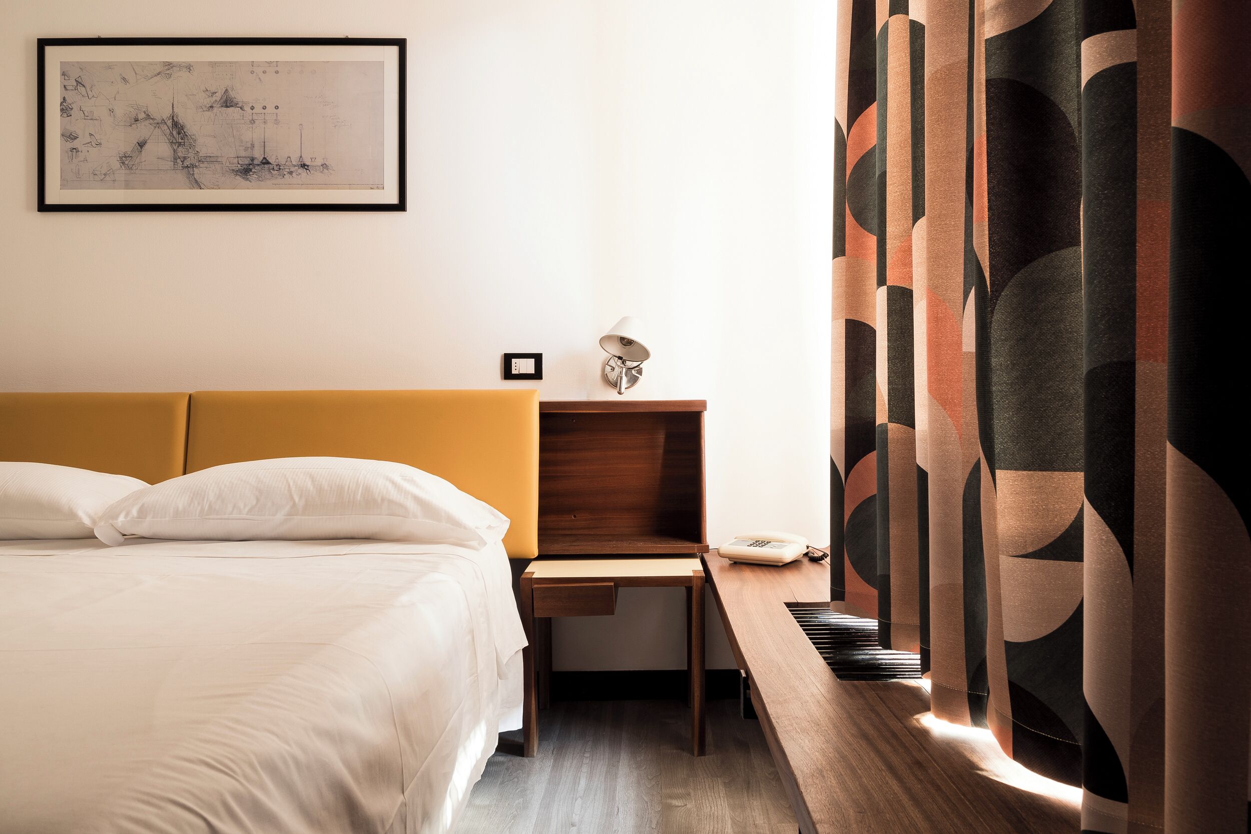 Una habitación de hotel con cama, escritorio, lámpara y teléfono en la pared.