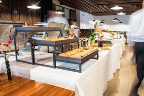 A buffet setup with multiple serving stations, including trays of pastries and a variety of condiments. - Hotel Boite (Borca di Cadore)