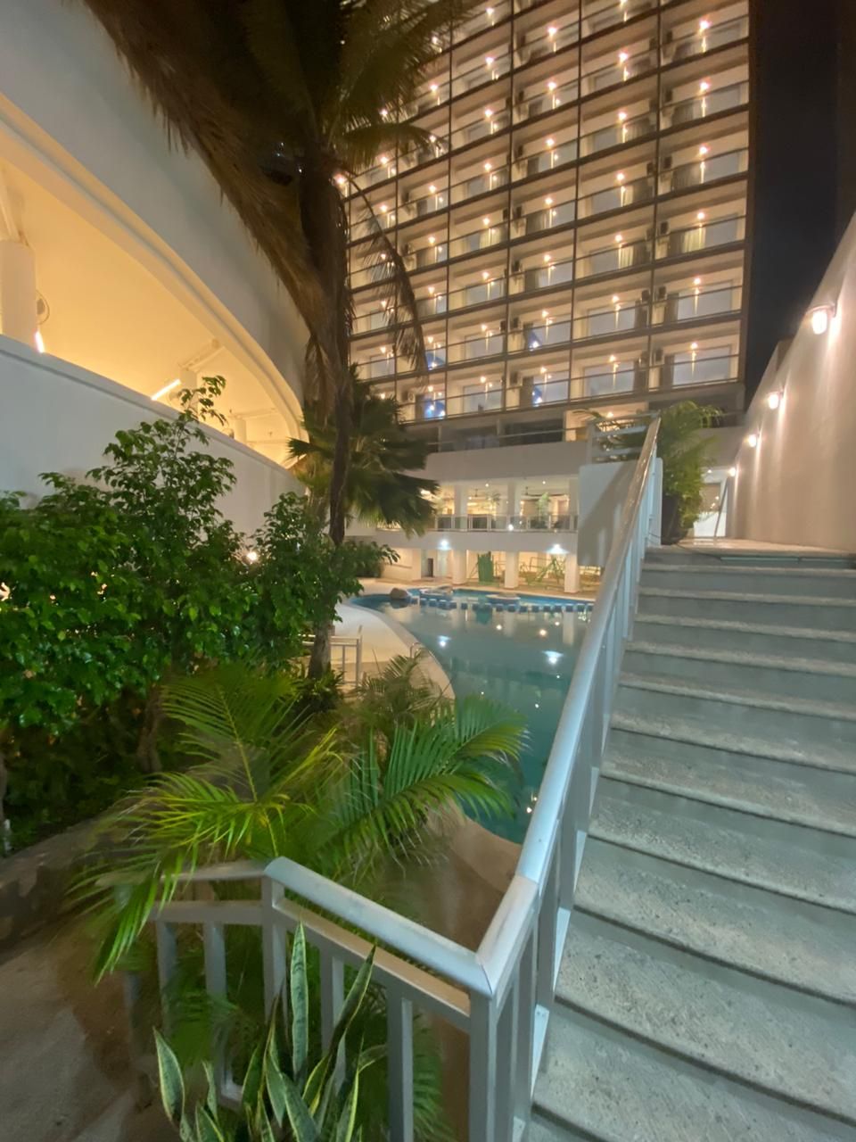 A staircase leading to a pool area with a view of a building with multiple balconies.