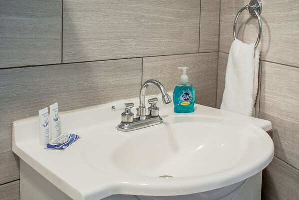 A bathroom with a white sink, a silver faucet, and a blue bottle of hand soap.