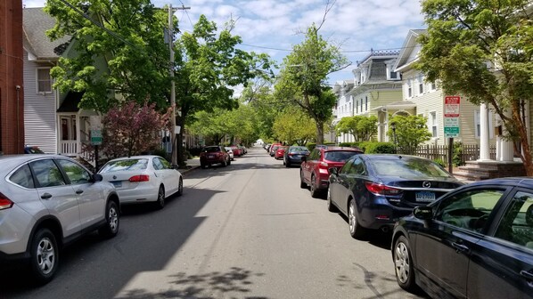 A residential street lined with parked cars and houses.