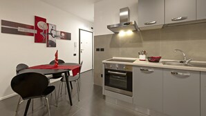 Una cocina moderna con horno empotrado, armarios de acero inoxidable y un mantel rojo sobre la mesa de comedor.