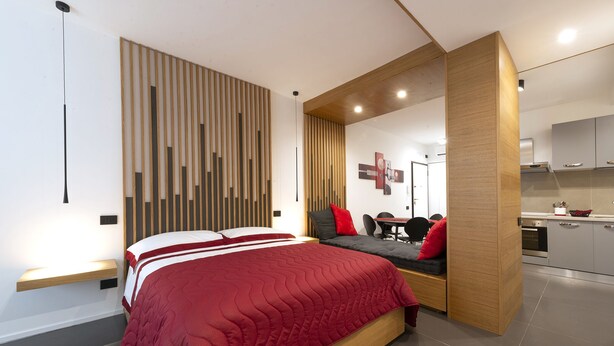 Un dormitorio moderno con una cama grande, un escritorio empotrado y una zona de kitchenette.