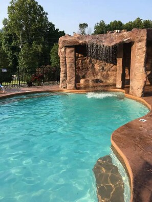 A clear blue pool with a rocky waterfall feature. - Easy Drive Resort Cabin w/ Hot Tub, Mtn View, and Resort Pool Near National Park (Gatlinburg)
