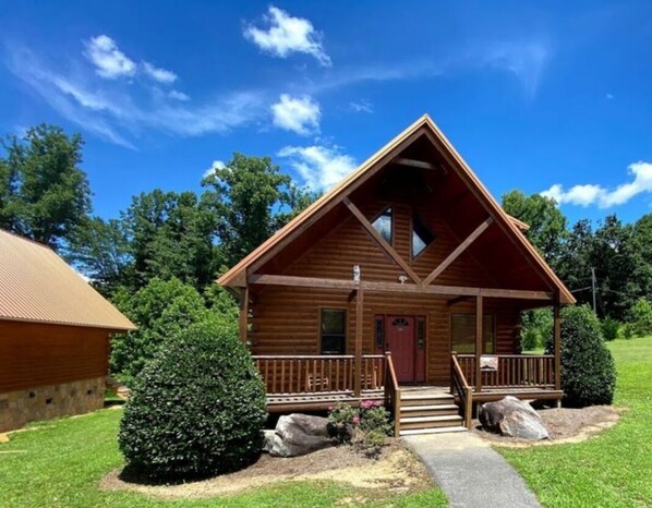 A wooden cabin with a front porch, a red door, and a small window. - Easy Drive Resort Cabin w/ Hot Tub, Mtn View, and Resort Pool Near National Park (Gatlinburg)
