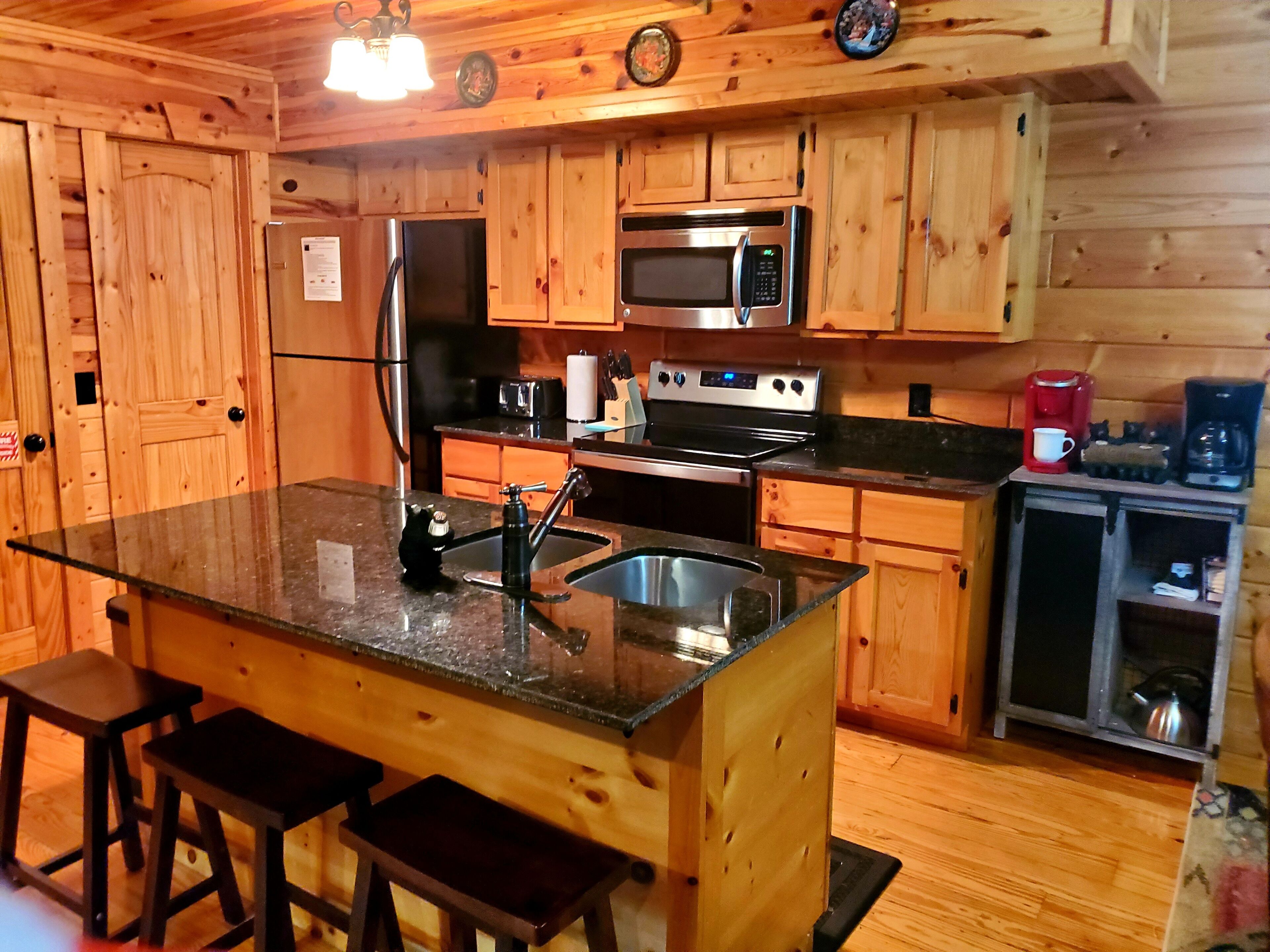 Cocina tipo cabaña de madera con una isla central, electrodomésticos de acero inoxidable y armarios de madera.