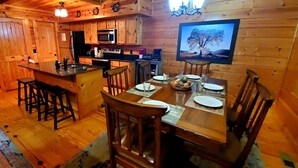 A wooden cabin interior with a kitchen, dining area, and a TV mounted on the wall. - Easy Drive Resort Cabin w/ Hot Tub, Mtn View, and Resort Pool Near National Park (Gatlinburg)