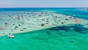 Vista aérea de una zona costera con numerosos barcos y yates en aguas turquesas cristalinas.