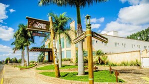 A hotel entrance with a sign reading "MEU HOTEL" and directional signs pointing to various amenities. - Meu Hotel Garça (Garca)