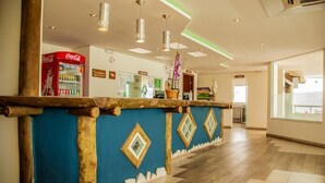 A reception area with a Coca-Cola refrigerator, a wooden reception desk, and a tiled floor. - Meu Hotel Garça (Garca)