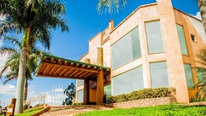 A hotel with a covered entrance, palm trees, and a clear blue sky. - Meu Hotel Garça (Garca)