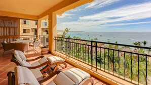 Een balkon met uitzicht op zee, voorzien van lounge fauteuils en een tafel.