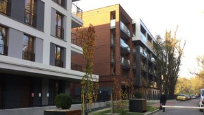 A modern apartment building with multiple balconies, a gated entrance, and a well-maintained lawn. - Apartment Go at Rakowicka street  located just few minutes walk from city center (Kraków)