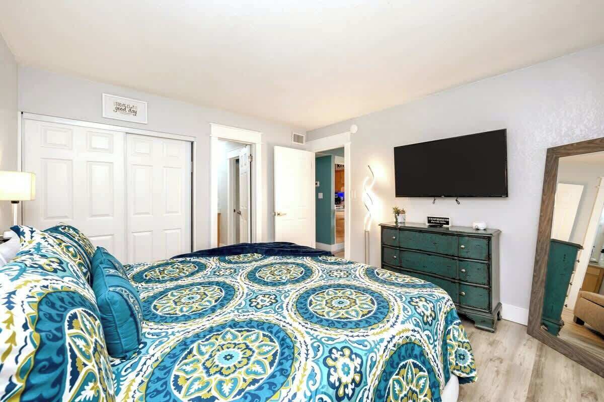 Une chambre avec un grand lit, une commode, un téléviseur fixé au mur et un miroir également fixé au mur.