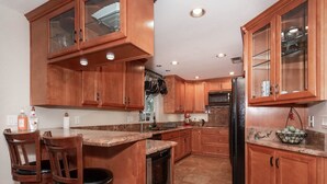 Une cuisine dotée de meubles en bois, de plans de travail en granit, d’un lave-vaisselle et d’un réfrigérateur.