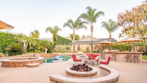 Un jardin avec une piscine, un foyer extérieur, un espace salon extérieur et un coin bar.
