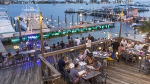 Un restaurante frente al agua con terraza al aire libre con vistas al puerto deportivo.