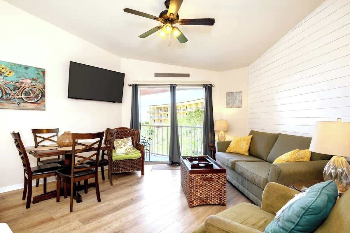 Ein Wohnzimmer mit Essbereich, einer Couch, einem Fernseher und einem Balkon mit Blick.