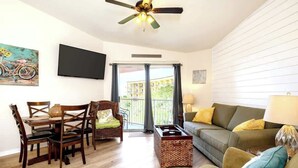 Una sala de estar con comedor, sofá, televisión y balcón con vistas.