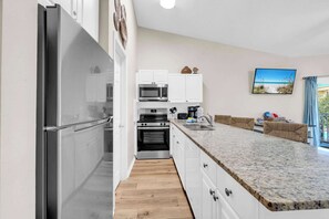 A modern kitchen with white cabinets, stainless steel appliances, and a granite countertop.
